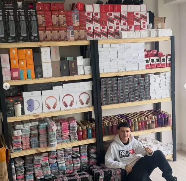 Thiago en su depósito con estanterías de perfumes y auriculares